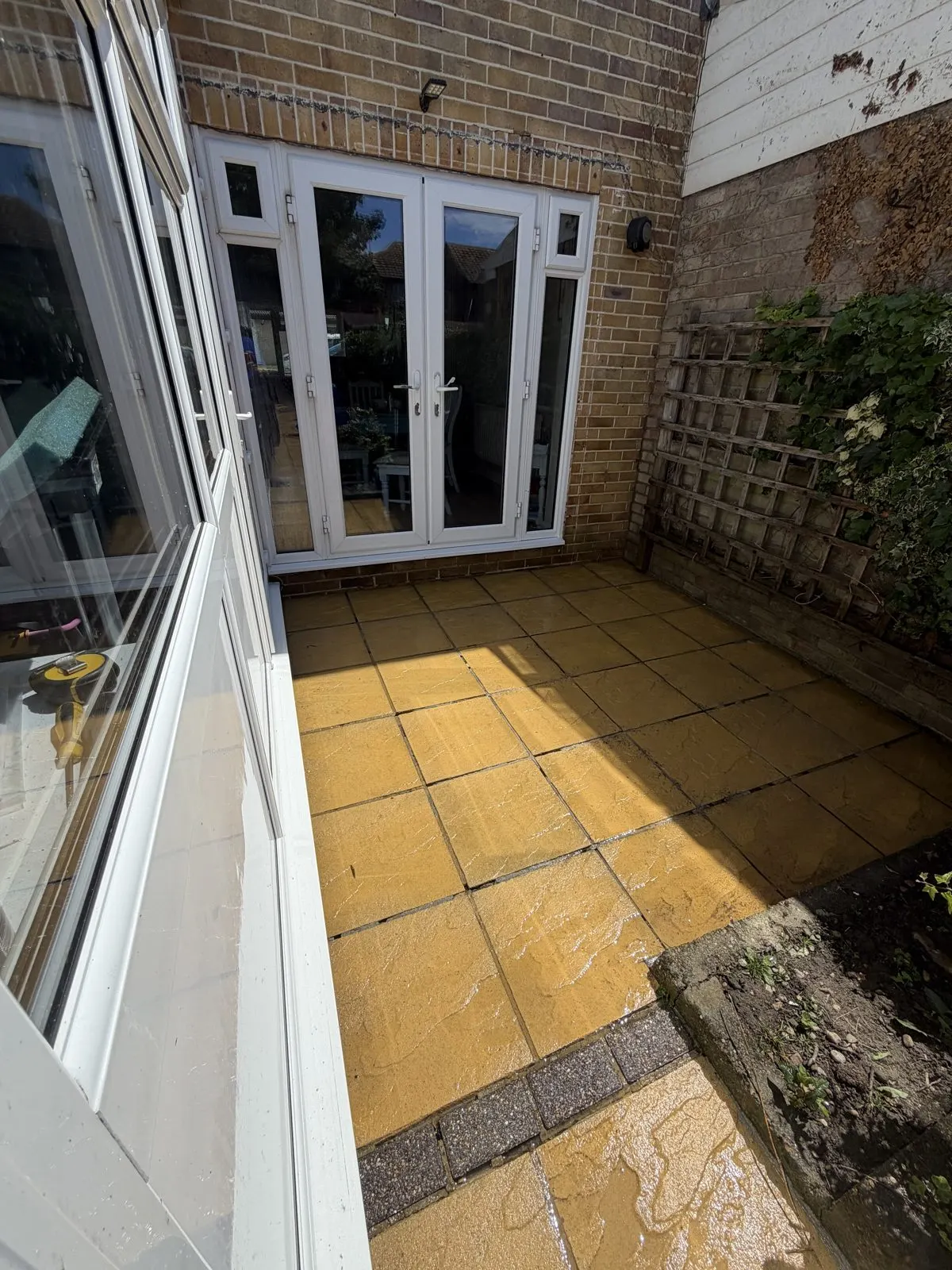 The same rear patio after cleaning, showing the original buff and yellow slab colour