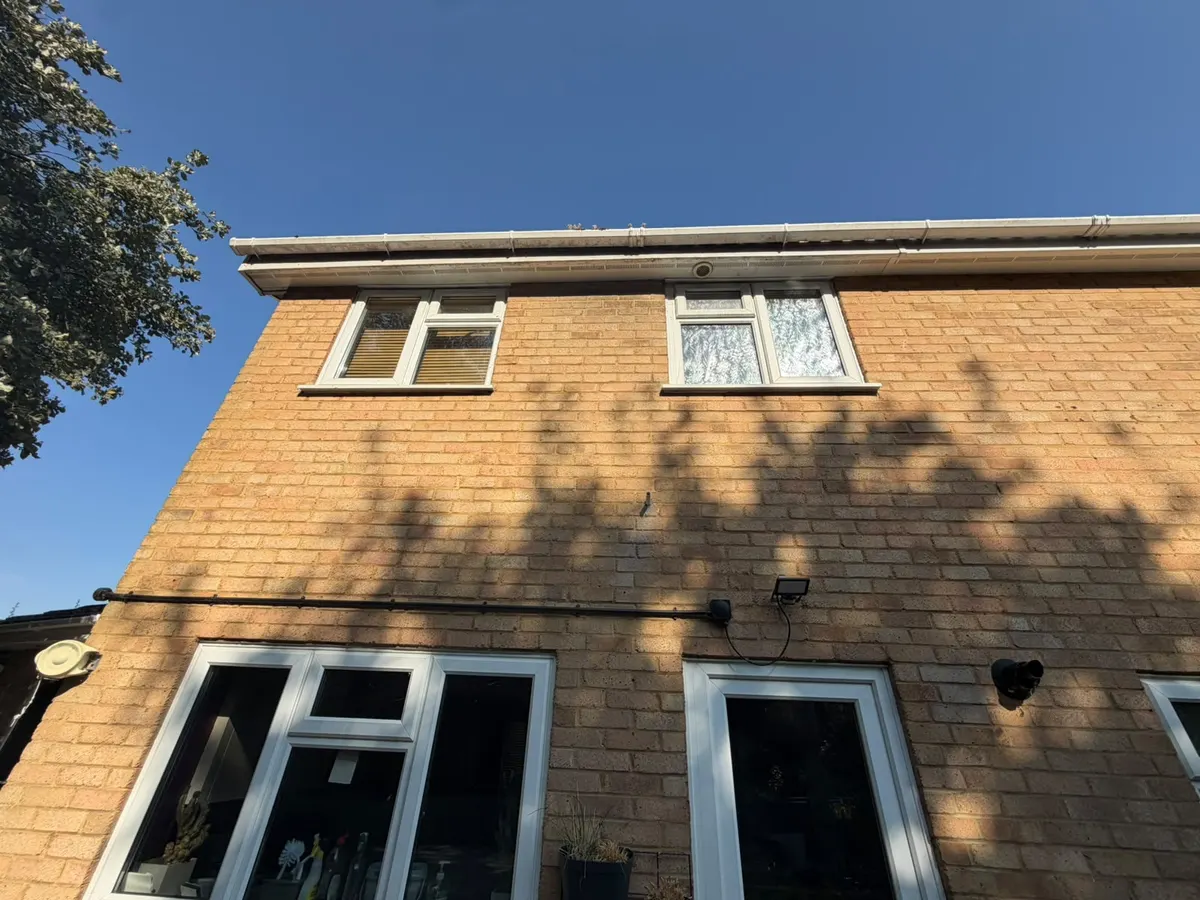 White uPVC gutter, fascia and soffit before cleaning, with grime streaks and growth on the gutter