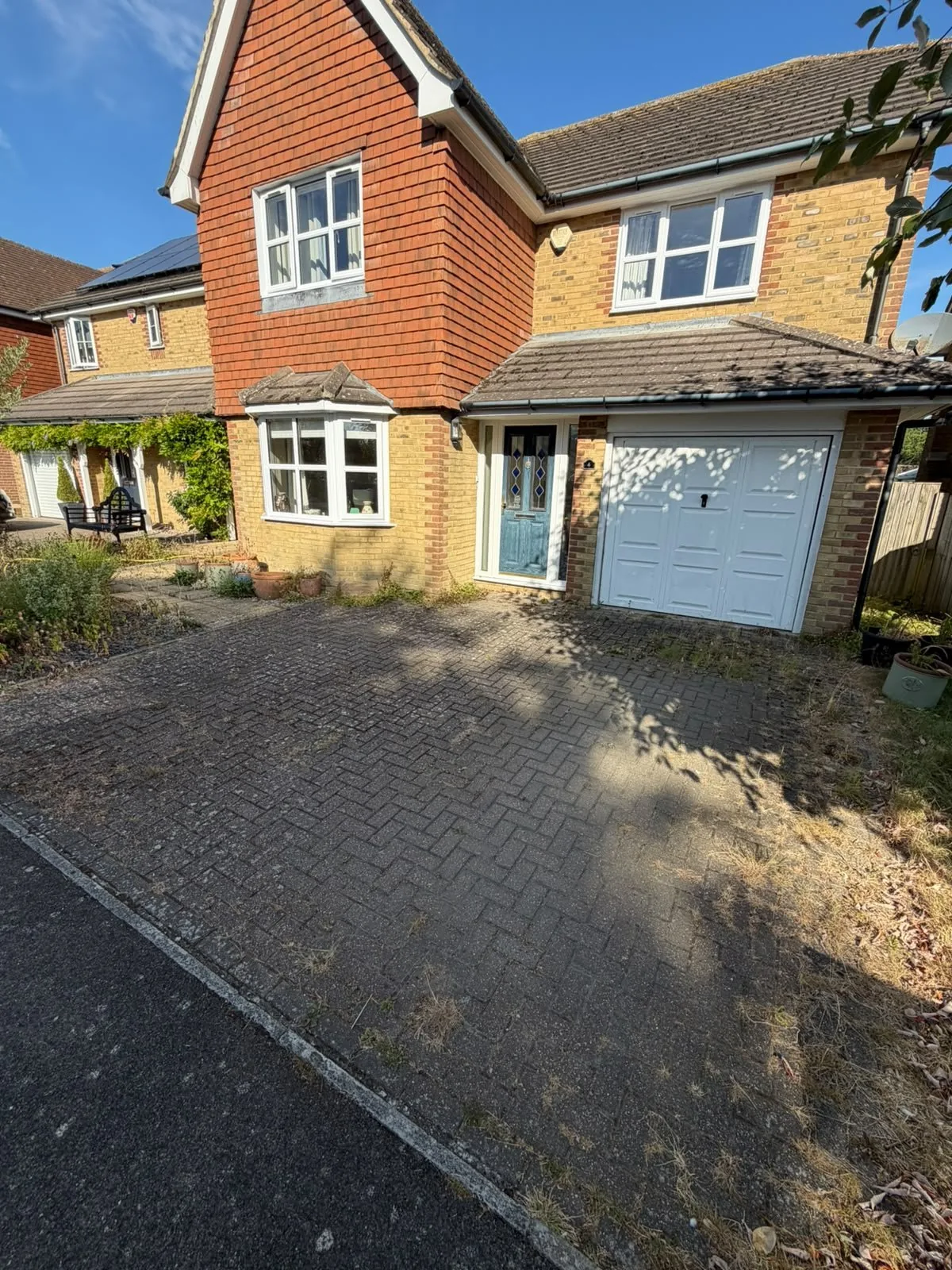 Block-paved domestic driveway before cleaning, with dark weathering across the paving