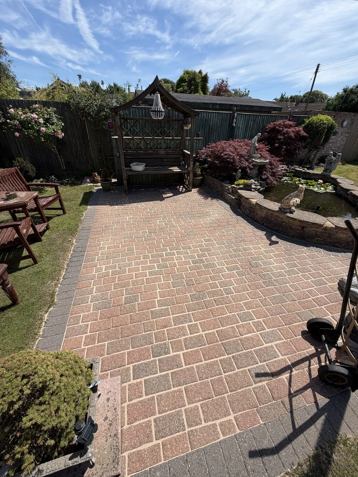 The same garden patio after cleaning, with the original red block paving clearly visible